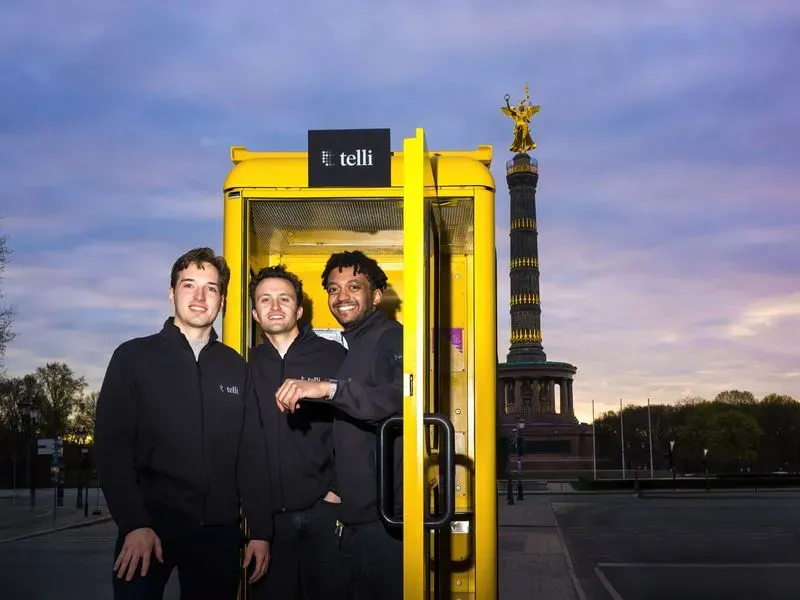 telli founders Seb, Finn, and Philipp in front of a yellow phone booth
